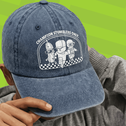Blue denim cap with Stumble Guys graphic design and text held by a person against a green background