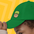 Load image into Gallery viewer, Green cap with a Mr. Stumble design on a yellow background

