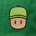 Load image into Gallery viewer, Embroidered Mr. Stumble, in green cap, on a green background.
